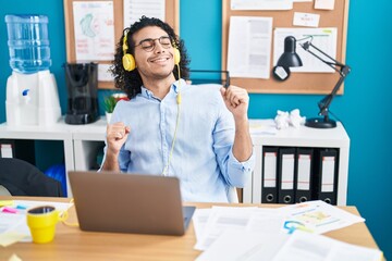 Young latin man business worker listening to music dancing at office