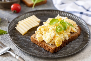 Homemade breakfast or brunch meal - scrambled eggs. Scrambled eggs on whole grain bread on a stone table.