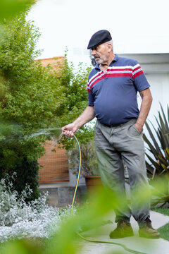 Senior man watering the plant in his garden at home.