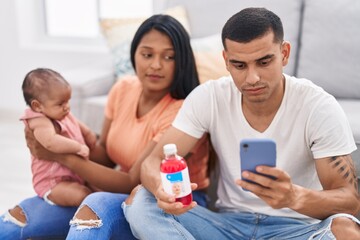 Hispanic family having telemedicine sitting on floor at home