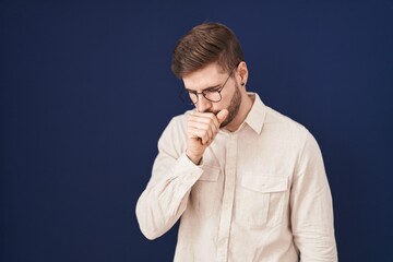 Hispanic man with beard standing over blue background feeling unwell and coughing as symptom for cold or bronchitis. health care concept.