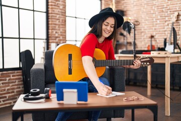 Young woman musician composing song at music studio