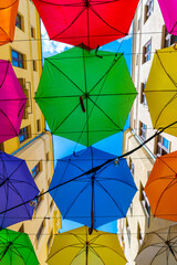 Ulica Piotrkowska w Łodzi i kolorowe parasole wiszące między budynkami nad błękitnym niebem. - obrazy, fototapety, plakaty