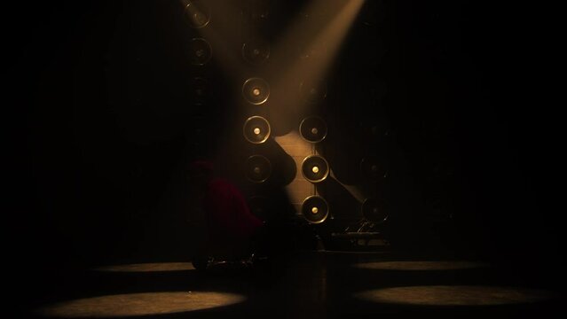 Sexy female stripper seducing client by erotic dance in private room of strip club. Moving spot lights catching erotic dancer in the dark, teasing with sexy moves of stretched legs and bright clothes