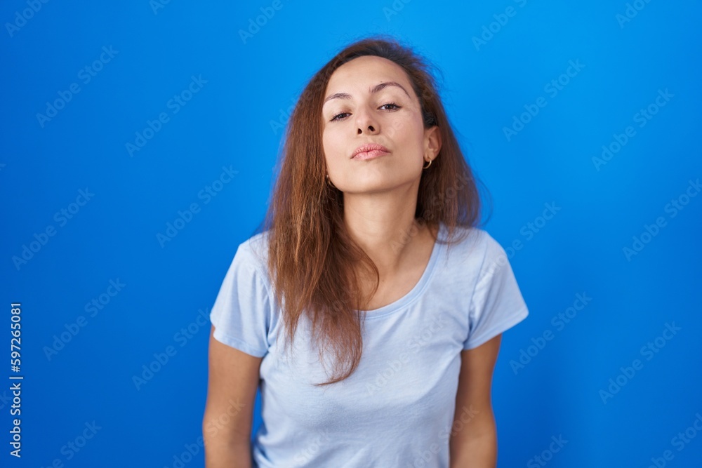 Canvas Prints brunette woman standing over blue background looking at the camera blowing a kiss on air being lovel