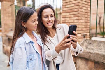 Woman and girl mother and daughter using smartphone at street