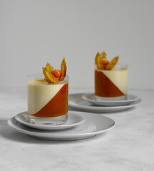 Panna Cotta with mango puree decorated with physalis. Delicious Italian dessert.