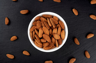 A bowl of almonds on the table. Scattering of almonds. Healthy snack with nuts.