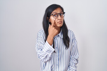Young hispanic woman wearing glasses pointing to the eye watching you gesture, suspicious expression