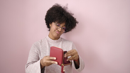 Young african american woman showing empty wallet over isolated pink background