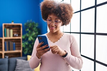 Fototapeta na wymiar African american woman smiling confident using smartphone at home