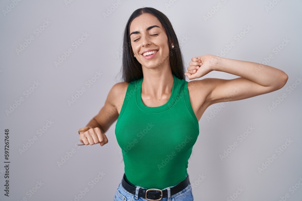 Wall mural Young woman standing over isolated background stretching back, tired and relaxed, sleepy and yawning for early morning