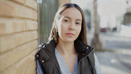 Young beautiful hispanic woman standing with serious expression at street