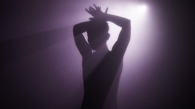Copy background with dancing shadow silhouette of beauty model girl. Beautiful sexy young woman perfect slim body moves hands in mysterious pink purple foggy light. Seduction Slow motion 4K RED camera