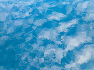 Clouds are reflected in the calm surface of the tropical Pacific Ocean.