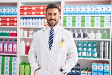 Young hispanic man pharmacist smiling confident standing at pharmacy