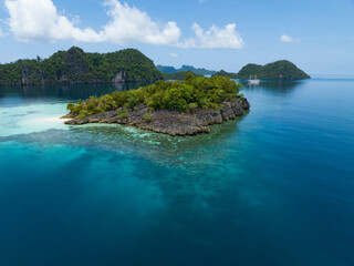 Fototapeta premium Beautiful coral reefs surround the dramatic limestone islands that rise from Raja Ampat's seascape. This remote part of Indonesia is known for its incredible marine biodiversity.