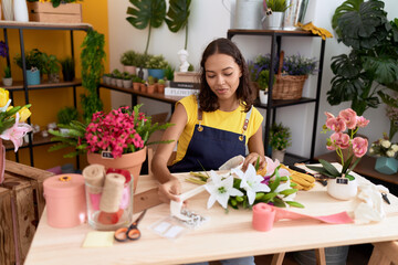 Young african american woman florist make bouquet of flowers at flower shop