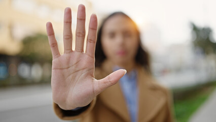 Young beautiful hispanic woman doing stop gesture with hand at street