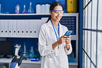 Young african american woman scientist using smartphone at laboratory