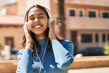 Young african american woman smiling confident listening to music at street