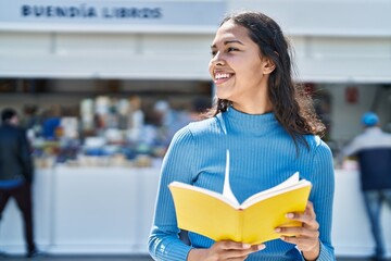 Young african american woman smiling confident reading book at street