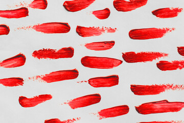 Smears of red cosmetic lipstick on a light background.
