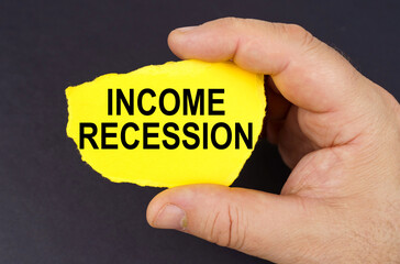 On a black background, in the hands of a man, a yellow torn cardboard with the inscription - income recession