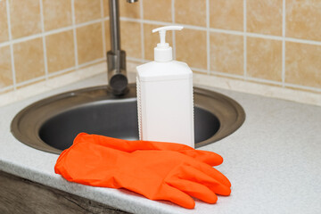 Kitchen sink with faucet and gloves for cleaning and detergent.