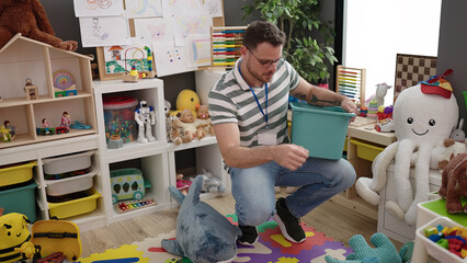 Young caucasian man working as teacher tidying up at kindergarten