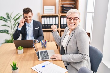 Middle age woman working at the office screaming proud, celebrating victory and success very...