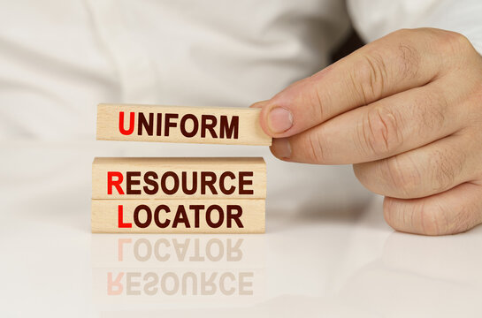 In The Hands Of A Person And On A Reflective Surface Are Wooden Blocks With The Inscription - Uniform Resource Locator