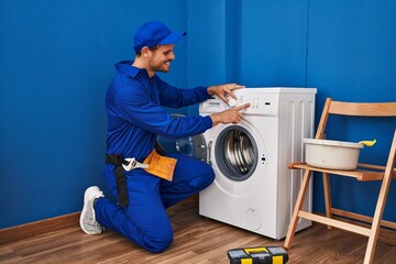 Young hispanic man technician turning on washing machine at laundry room