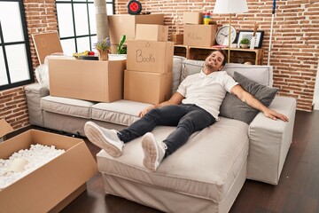 Young hispanic man relaxed sitting on sofa at new home