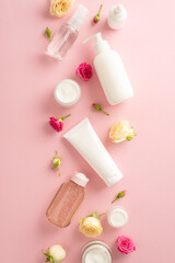 Discover the beauty of nature with this tender skincare concept. Top view flat lay of pump bottle, pipette, and cream bottles on a pastel pink background