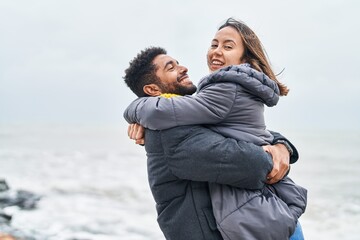 Man and woman couple smiling confident hugging each other at seaside