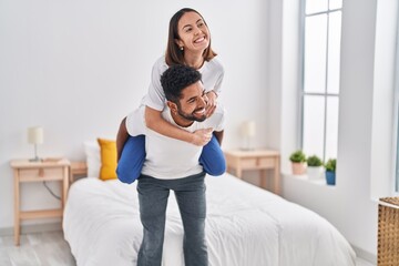 Man and woman smiling confident holding girlfriend on back at bedroom