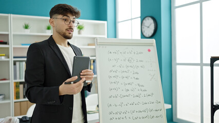 Young arab man teacher teaching maths lesson using touchpad at university classroom