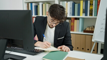 Fototapeta na wymiar Young arab man student using computer writing on notebook at university classroom