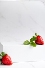 White podium with strawberry on marble background. Pedestal podium for product placement display....