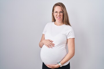 Young pregnant woman expecting a baby, touching pregnant belly clueless and confused expression....
