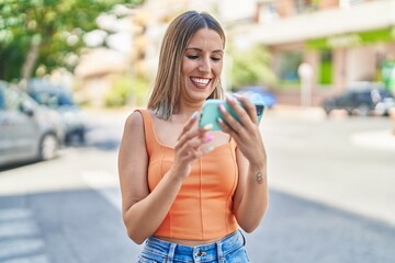 Young beautiful hispanic woman smiling confident watching video on smartphone at street