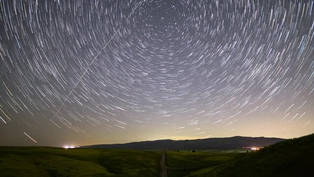 Time lapse of star trails over dirt road during wildflower superbloom in Southern California
