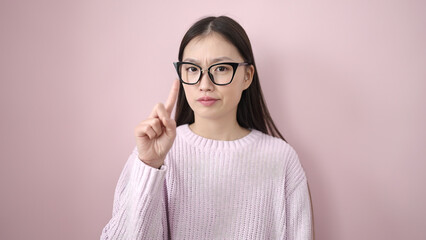 Young chinese woman doing no gesture with finger over isolated pink background