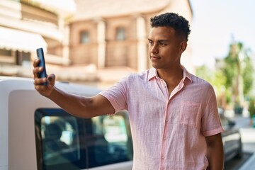 Young latin man smiling confident making selfie by the smartphone at street