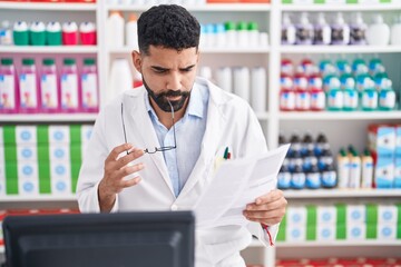Fototapeta na wymiar Young arab man pharmacist reading document with doubt expression at pharmacy