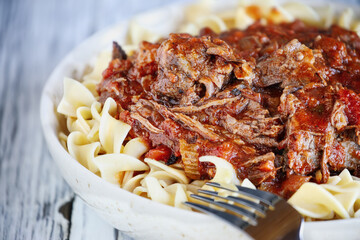 Hearty bowl of fresh homemade beef ragu over cooked egg noodle pasta. Extreme shallow depth of field with blurred foreground and background.