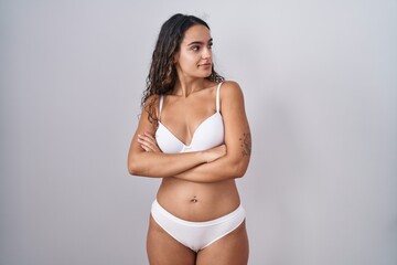 Fototapeta premium Young hispanic woman wearing white lingerie looking to the side with arms crossed convinced and confident