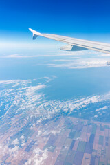 Fototapeta premium View from the airplane window at a beautiful cloudy sky and the airplane wing