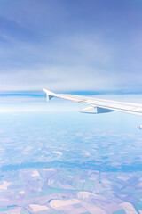 Aerial view from airplane window above green ground. View from the airplane window with beautiful clouds at sunrise